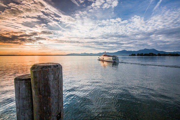 Das Foto zeigt ein Schiff auf dem Chiemsee. Dahinter befindet sich ein Sonnenuntergang.