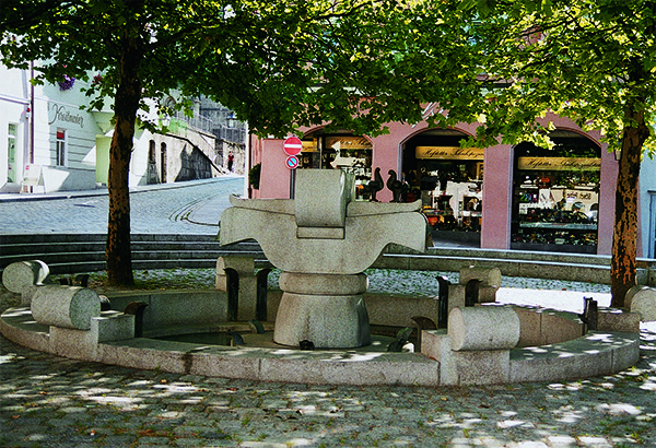 Das Foto zeigt den Taubenbrunnen am Vormarkt. Steinfiguren und Tauben aus Metall.