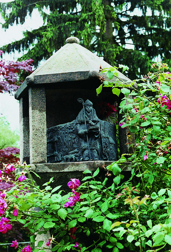 Das Foto zeigt den Bischof von Ravenna aus Bronze, der auf einem Stein-Sockel sitzt.