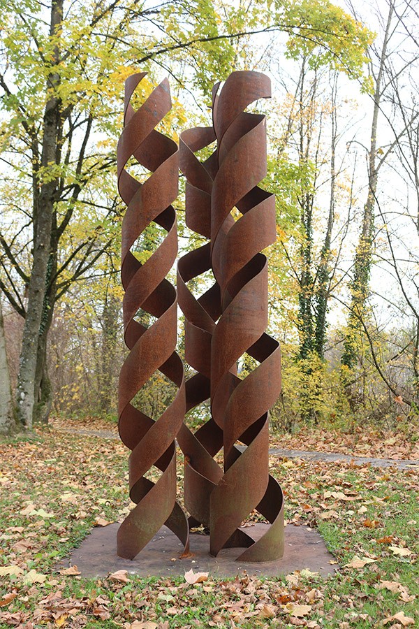 Das Foto zeigt drei in sich verdrehte, verrostete Spiralen aus Stahl.