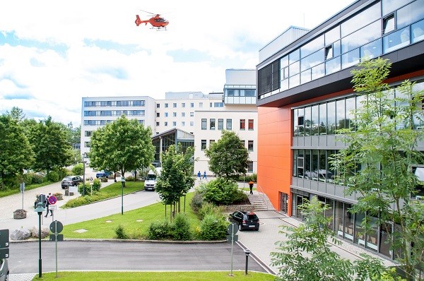 Das Foto zeigt die Kreisklinik Traunstein in der Außenansicht mit dem Rettungshubschrauber Christoph 14.