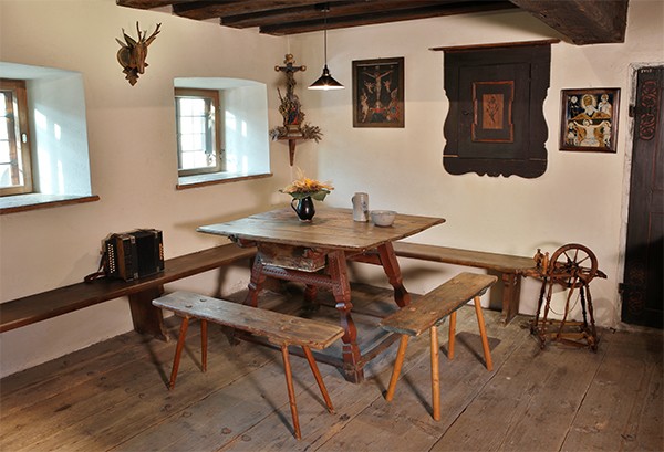 Bauernstube mit einer Eckbank, Bänken und Tisch aus Holz