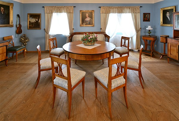 Tisch mit Stühlen in der Mitte, an der Wand hängt ein Bild von Helene Sedlmayr