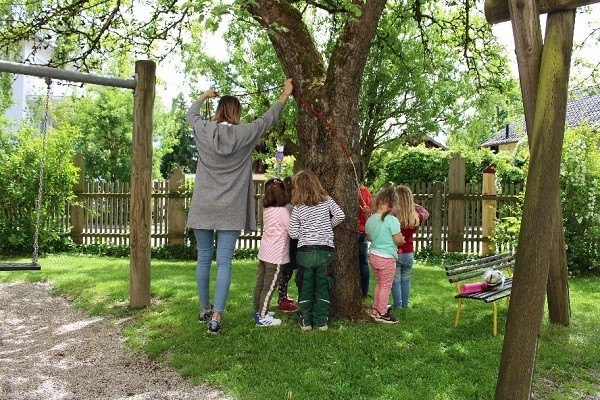 Kinder binden Kordeln um einen Baum