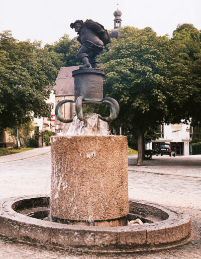 NEUSTIFTER, Josef: „Pienzenauer-Brunnen“, 1983, Bronzeguss, zur Erinnerung an Hans von Pienzenau, „Pfleger und Kastner zu Trostpurg“ († 1504). Unterer Marienplatz